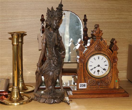 A late Victorian carved oak timepiece, a pair of brass candlesticks, a toilet mirror and a carved figure